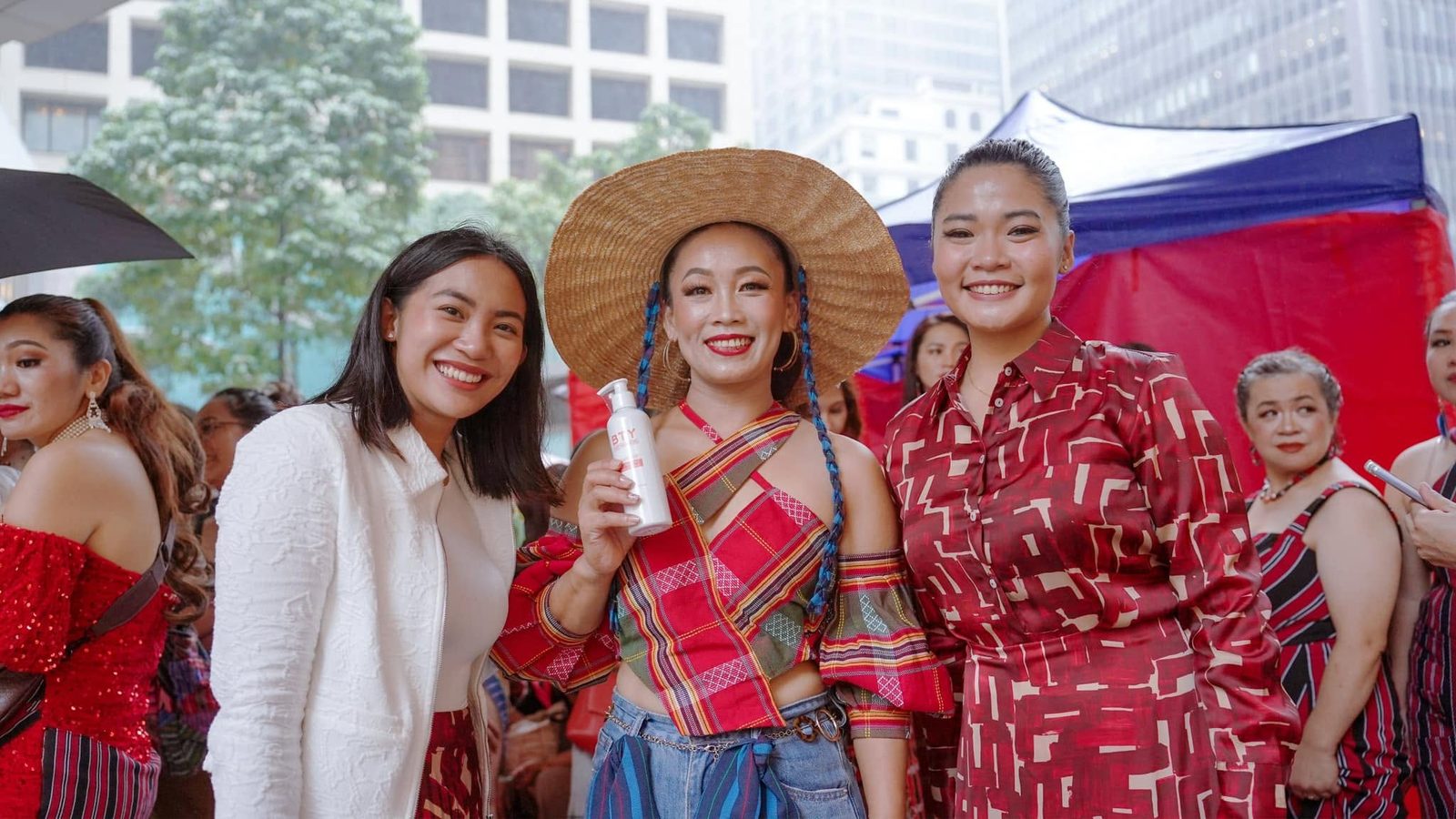 Three members of the BTY community at a Filipino cultural festival, one holding a BTY Advance bottle