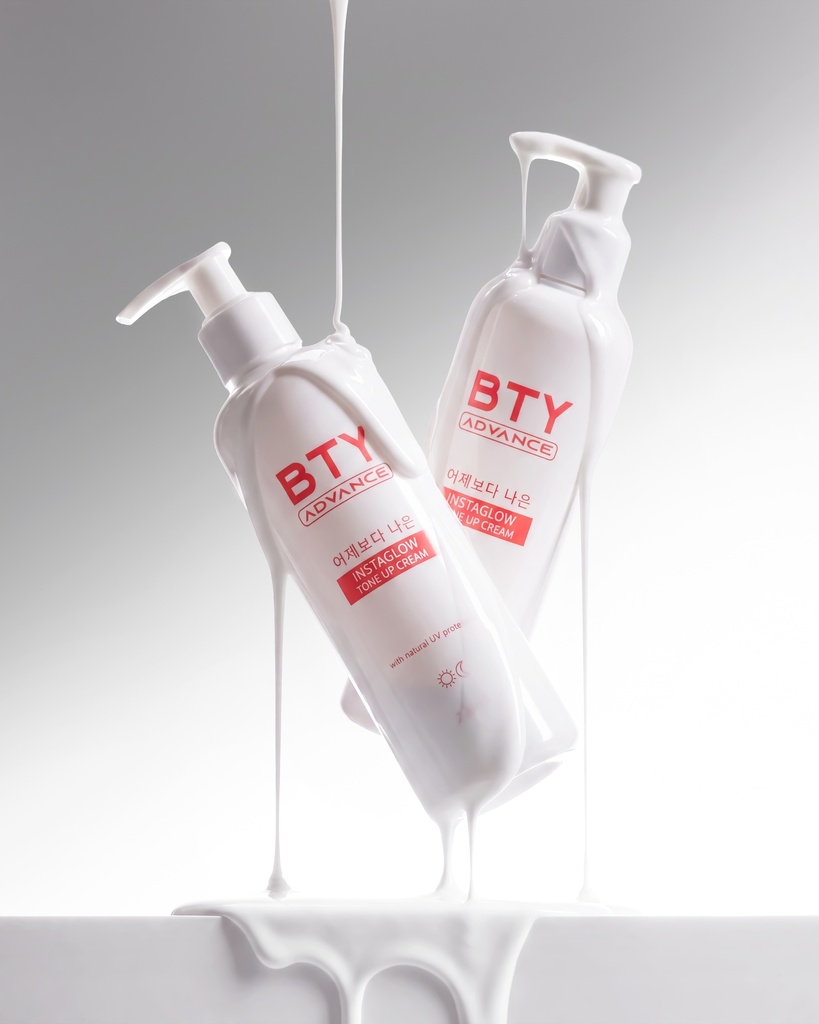 Two BTY Advance Instaglow Tone Up Cream bottles on table with city view