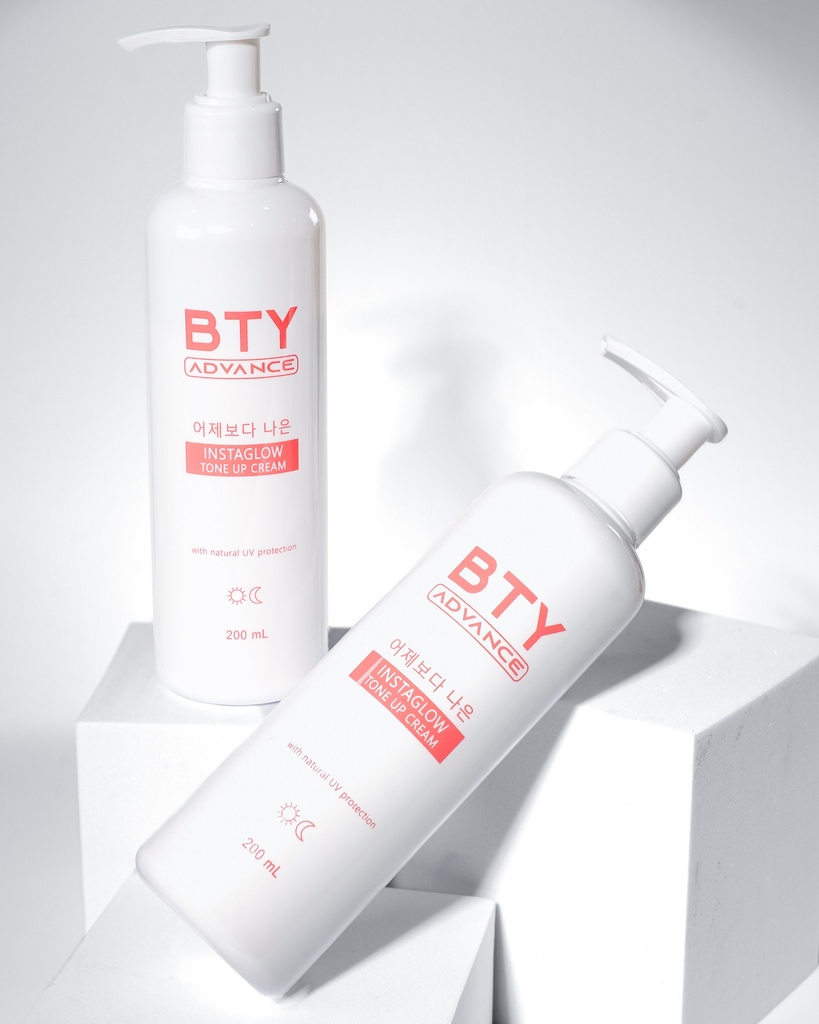 Two BTY Advance Instaglow Tone Up Cream bottles on a table with pink flowers
