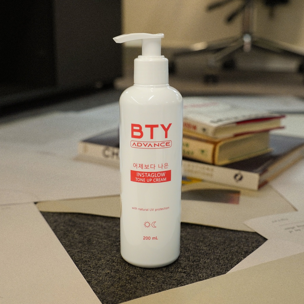 BTY Advance Instaglow Tone-Up Cream 200ml pump bottle on desk with books