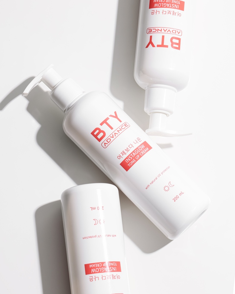 BTY Advance Instaglow Tone-Up Cream 200ml pump bottle on desk with books